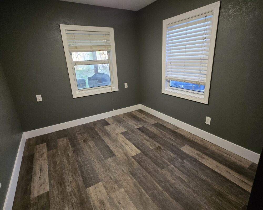 Interior view of a freshly remodeled room featuring dark gray walls, modern window treatments, and new wooden flooring, showcasing TurnKey Builds' craftsmanship in home renovations.