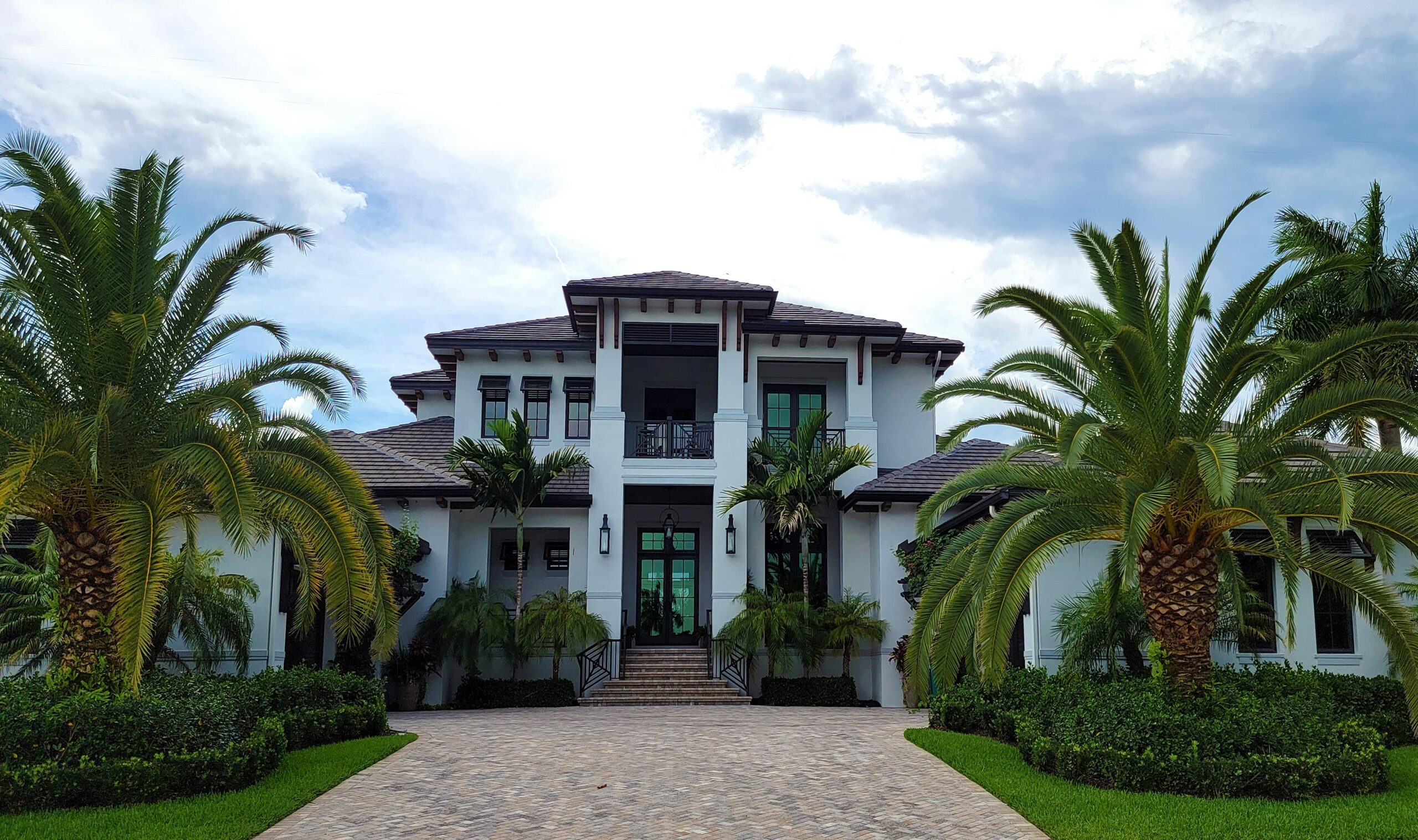 Luxury coastal home in Delray Beach, Florida, featuring palm trees, a spacious front entrance, and modern architectural design.