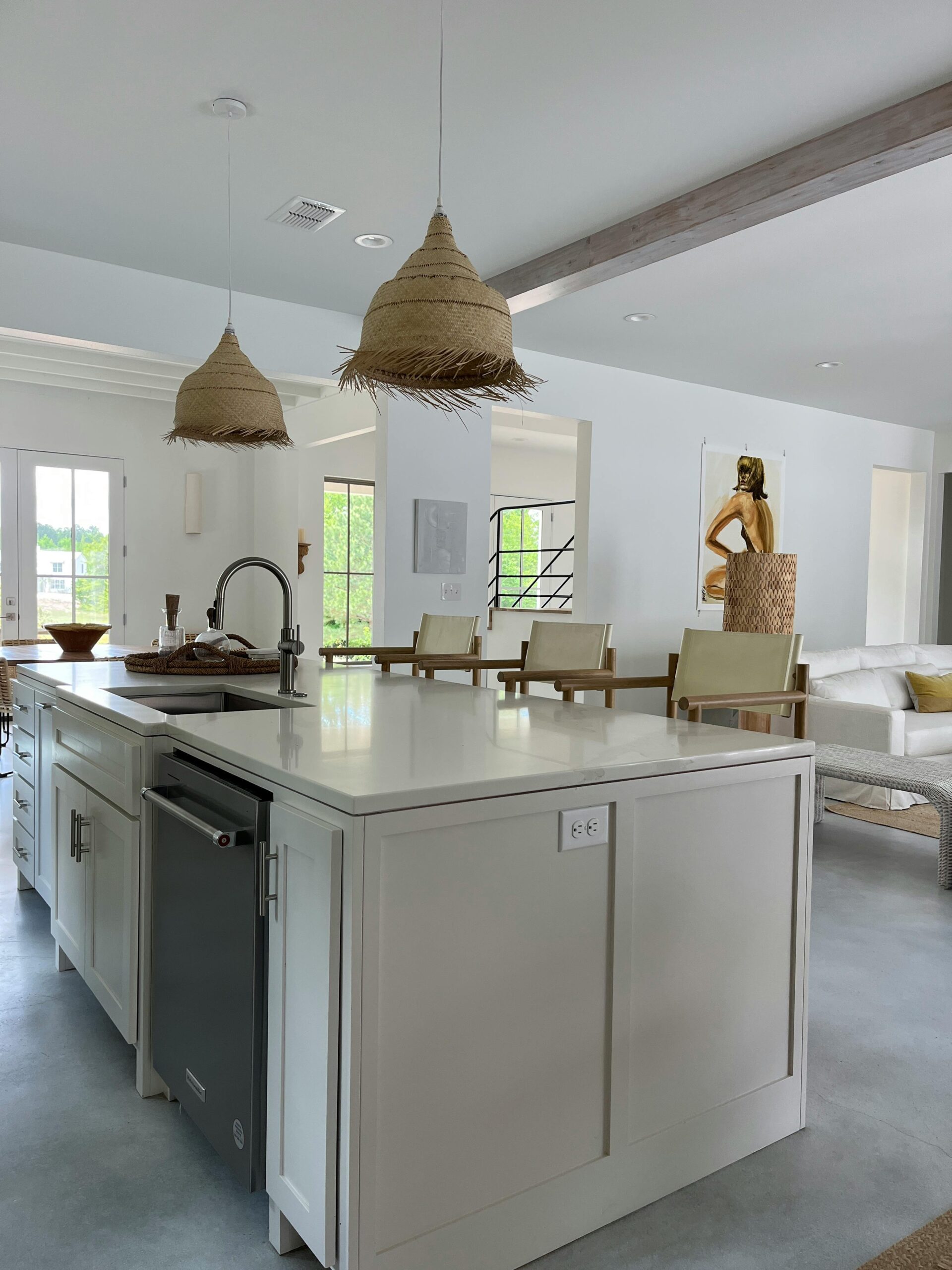 Modern kitchen interior featuring a white island with a built-in dishwasher, pendant straw lights, and a spacious open layout, emphasizing contemporary design and functionality for home renovations in South Florida.