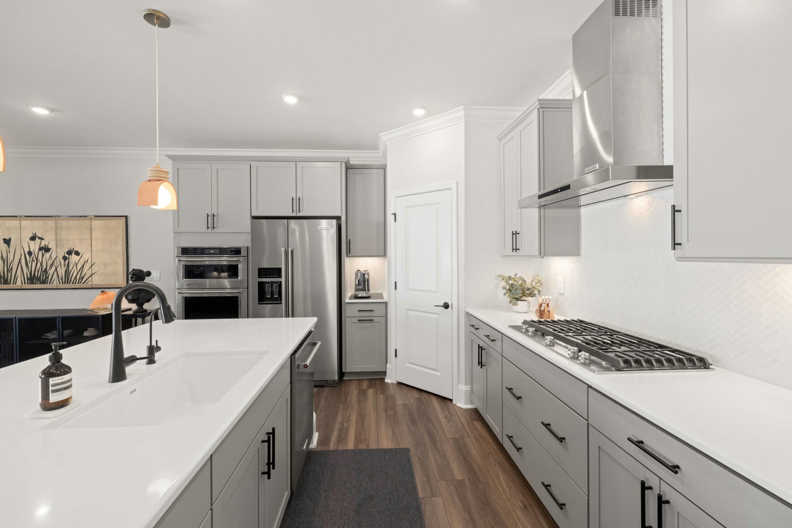 Modern kitchen interior featuring gray cabinetry, stainless steel appliances, and a spacious island with a sink, emphasizing contemporary design and functionality for home remodeling.