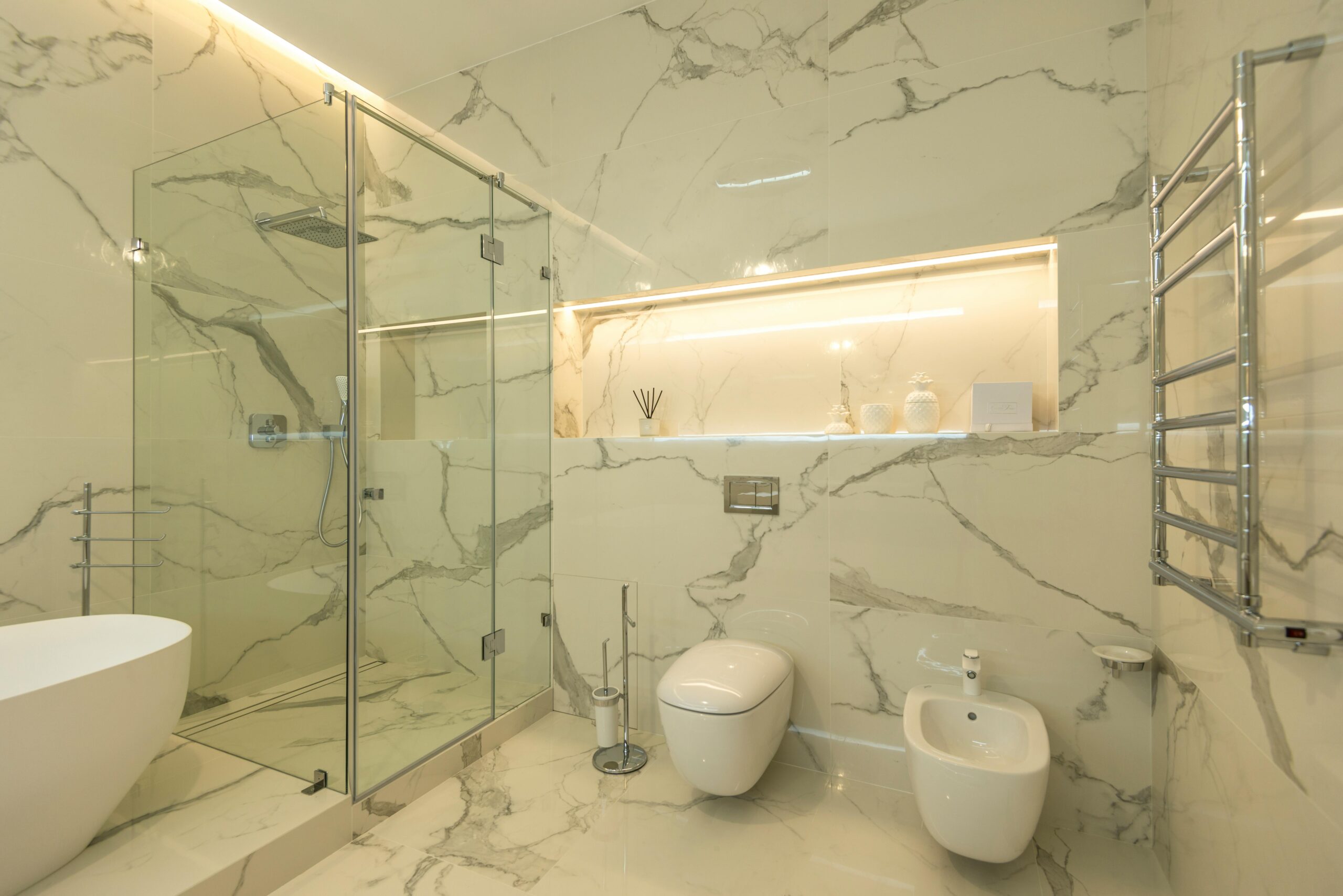 Modern bathroom design featuring a glass shower enclosure, freestanding bathtub, and elegant marble walls, emphasizing luxury and functionality in home remodeling.